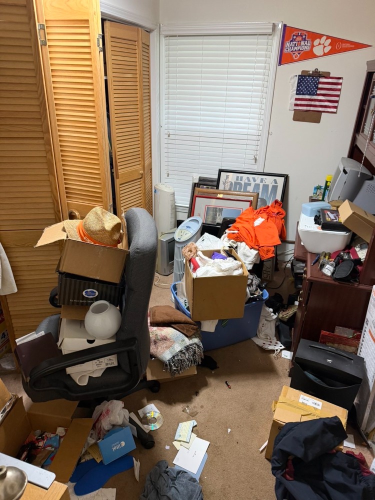 Cluttered spare room packed with boxes, furniture and household junk before removal